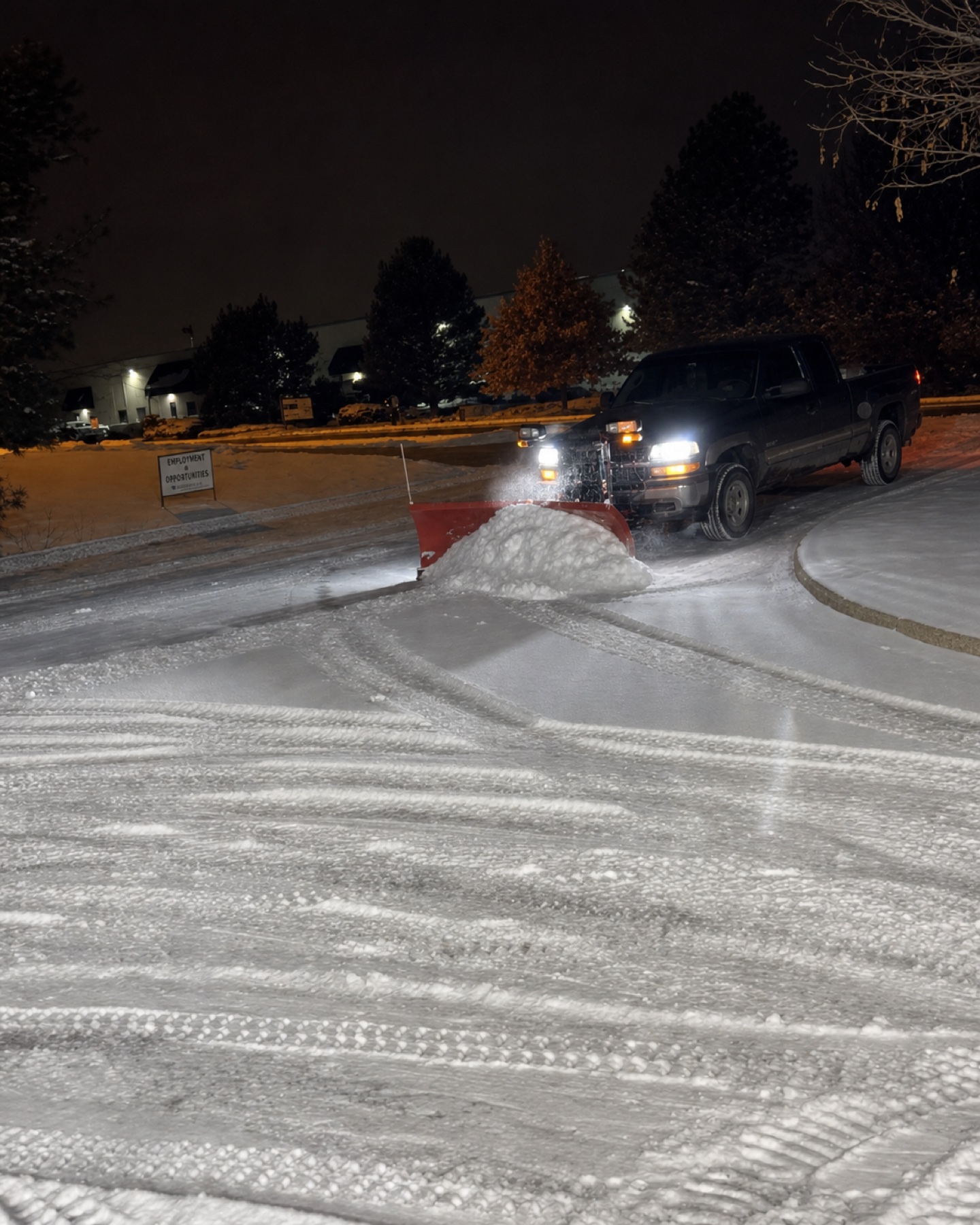 Commercial snow plow pushing snow during nighttime service